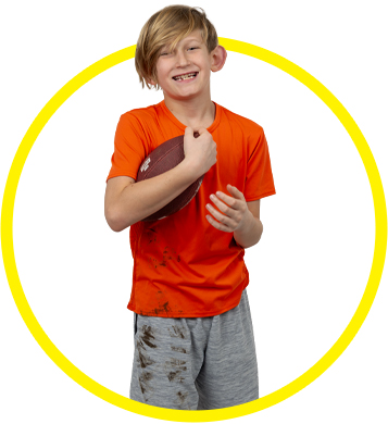 boy holding football with dirt stains on clothing